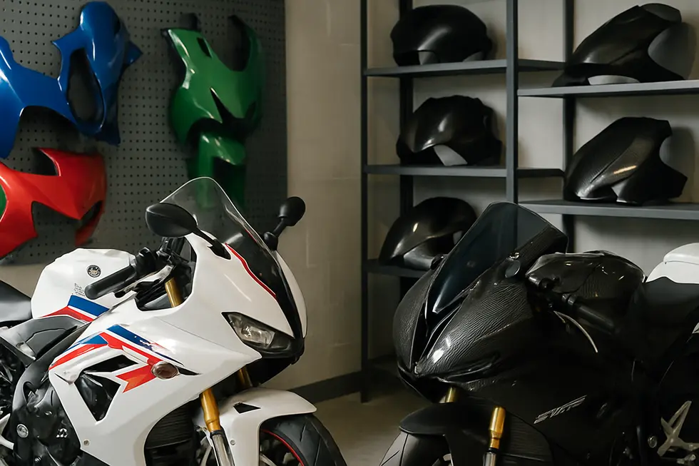 A display of diverse motorcycle fairings including ABS plastic and carbon fiber models arranged in a professional workshop and retail environment.