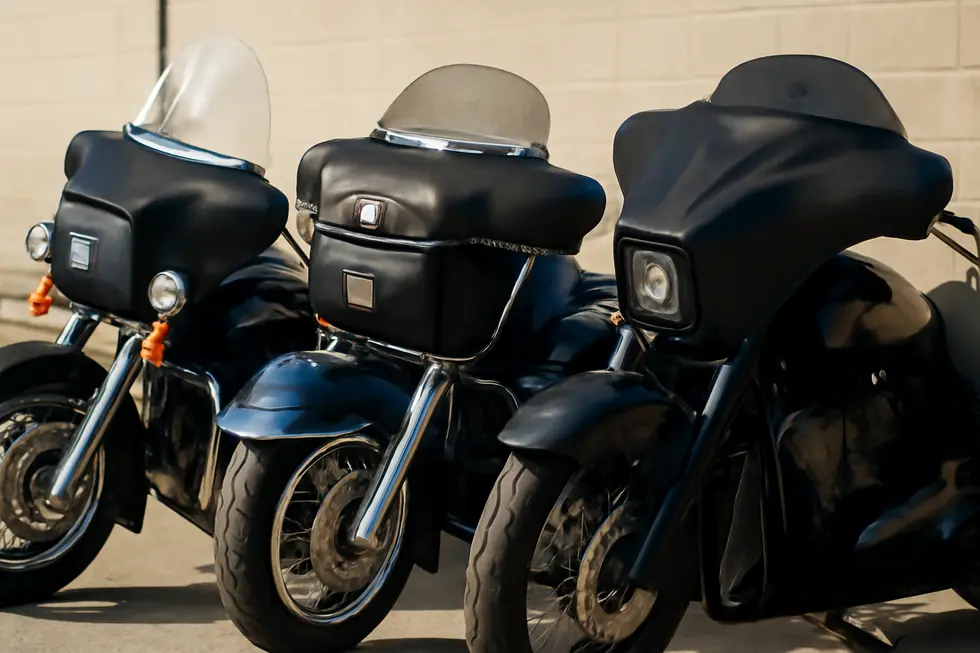 Three motorcycles featuring different fairing bags: a model-specific touring pouch, vintage replica police bags with brackets, and a custom stretched bagger bag in a well-lit showroom.